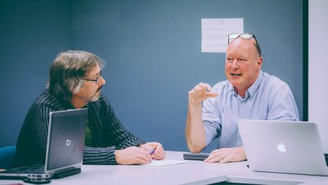 Two mature age staff talking