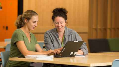 Woman helping girl at a laptop