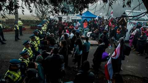Protestors are pictured behind a line of police officers: Against huge odds, the response of people now gathering at Ihumaatao is deeply authentic and honourable. Photo: Julie Zhu Photography