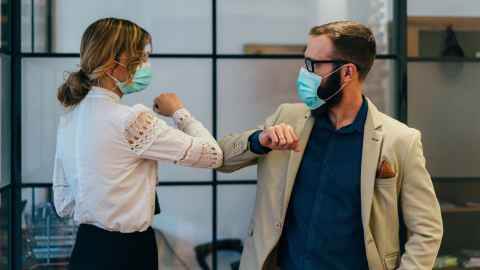 A couple are pictrured wearing face masks and rubbing elbows - but Tanish Jowsey asks: "Should we cough into our elbows and then minutes later have an ‘elbow shake’"?