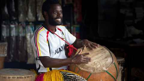 Alfdaniels Mabingo in Ugandan shirt and with drums.