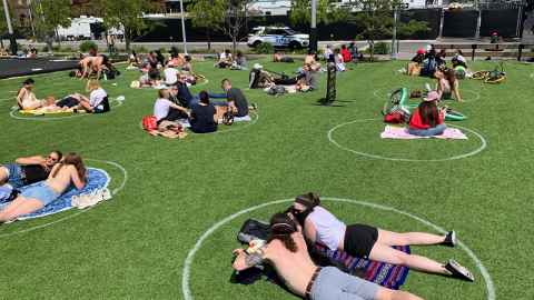 The image shows Domino park in Williamsburg, New York, where people are sitting in large white circles marked on the grass to accommodate social distancing. Photo: iStock