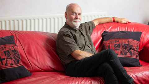 Jeremy Salmond is a renowned conservation architect. He is reclining on a red couch.