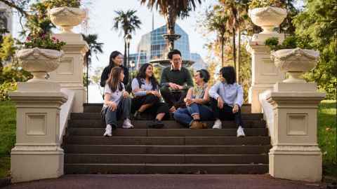 Group of international students sitting on steps at Albert Park.