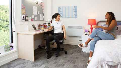 Students working around a table with laptops open.