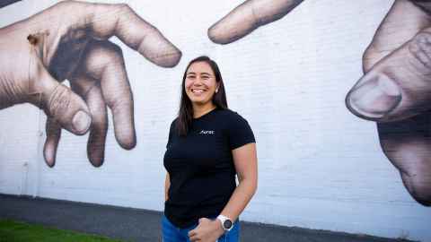 Kylene Jones in front of a mural with hands. 