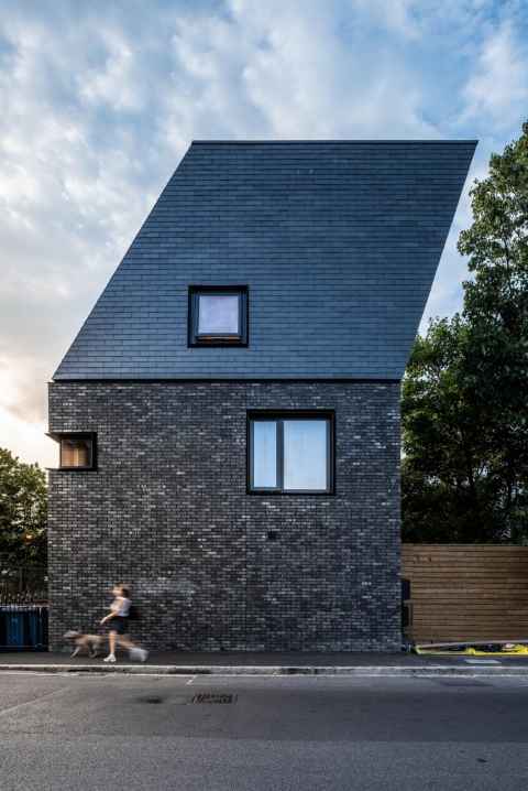 The award-winning development on the corner of Costa Street and McDermott Road, Peckham in London. Natural slate upper half, designed as a contemporary mansard leans into trees. 