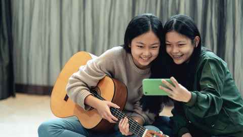 Two girls record song on phone.