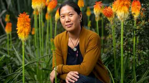 Dr Jin Russell in front of red-hot poker flowers.