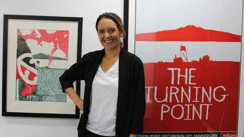 Dr Sarah-Jane Paine (Tūhoe) in front of two paintings.