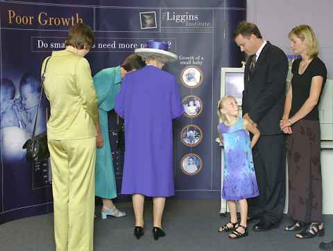 Queen is shown Professor Dame Jane Harding's work (obscured) with PM Helen Clark at Liggins 2002.