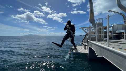 Dive safety officer Paul Caiger enters the water from Te Kaihōpara