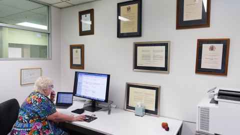 Dame Margaret Brimble in her office with walls adorned by her numerous awards. 