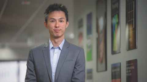 Award-winning bioengineer Dr Peng Du standing beside images of body organs in the ABI.