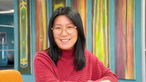 A landscape portrait of Dr Ying Wang with a colourful background behind her.