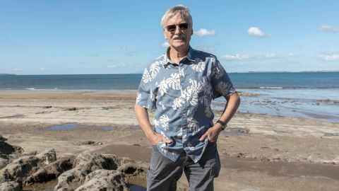Dr Kevin Trenberth says warmer oceans can fuel storms that lead to devastating floods. He is pictured standing on the beach on a sunny day. 