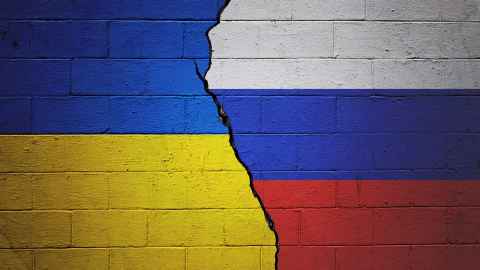 Cracked brick wall painted with a Ukrainian flag on the left and a Russian flag on the right.