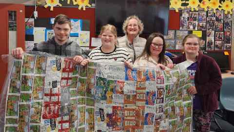 Children, pictured with Chip Packet Project founder Terrena Griffiths, holding up a chip packet blanket they have helped make. 