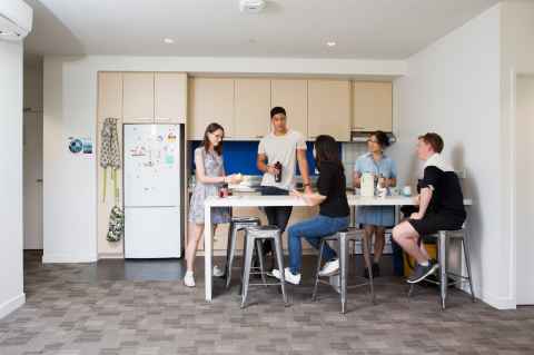 Group of five people around a high kitchen table chatting