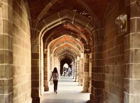 Students walking through arched stone walkway.