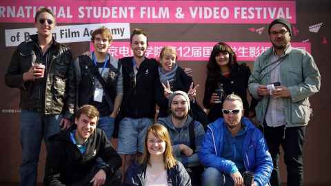 Group of happy students in front of a Beijing Student Film Festival' sign.