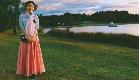 Hui Yu stands in front of a lake at sunset.