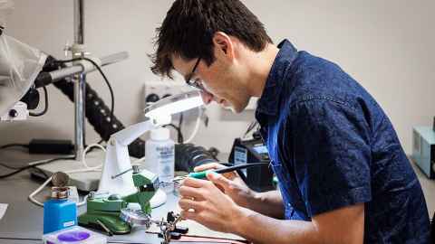 Kieran working with materials and tools in a lab.