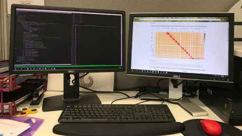 A tidy workplace holding two computer screens, each showing data.