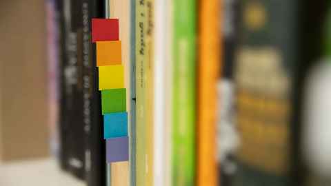 Image of books on shelf with rainbow post its