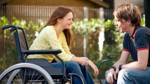 Two people sitting and chatting. One is in a wheelchair